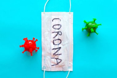 Parlak mavi arka planda Corona ve Coronavirus modelli tıbbi maske. Covid-19 konsepti