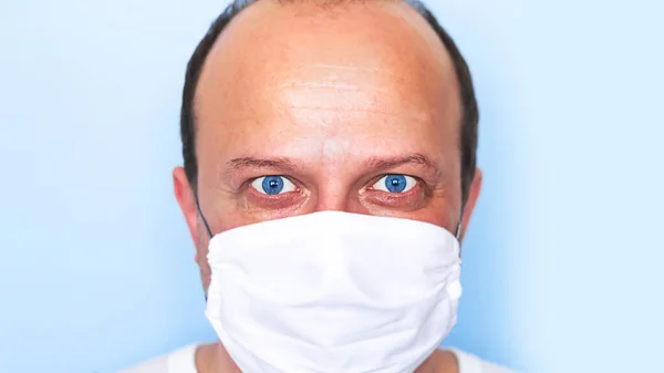 Portrait of a man with blue eyes in a medical mask. Covid-19 concept.