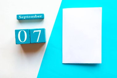7 Eylül. Ahşap el yapımı takvim ve geometrik beyaz ve mavi arkaplan üzerinde beyaz model boş