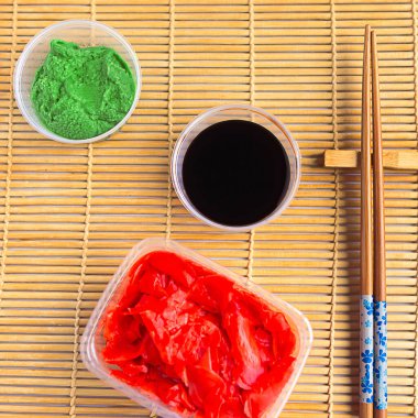 Wasabi, zencefil, soya sosu ve suşi arkaplanda yemek çubukları, üst manzara.