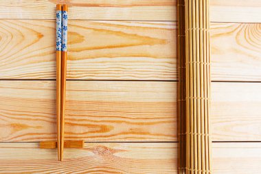 Çin yemek çubukları ve suşi paspası ahşap masada yuvarlanıyor.