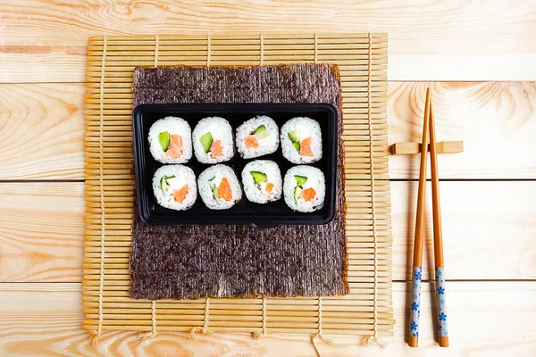一套寿司卷和木制背景的中国筷子 — 图库照片