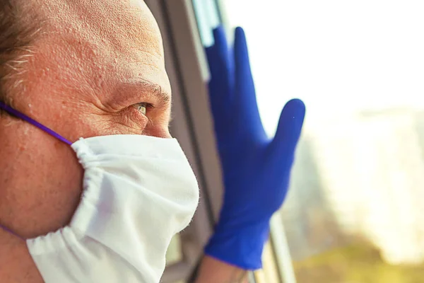 医療保護マスクの男が窓の外を見ている コロナウイルスの概念 検疫の概念 — ストック写真