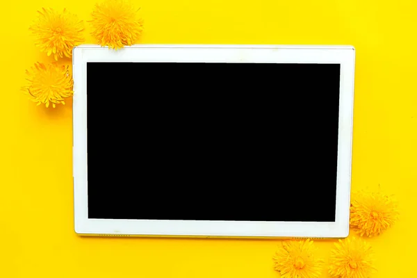 黄色の背景に黒いモックアップ画面と黄色のタンポポとタブレット テキストのスペースをコピーします 春のコンセプト — ストック写真