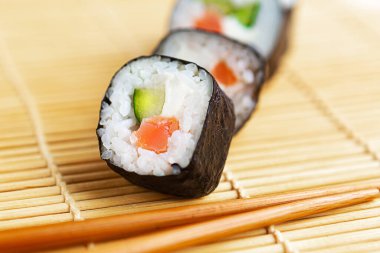 Suşi ruloları ve yemek çubukları. Arka planda, yakın planda, en üstte.