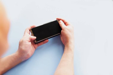 Beyaz arkaplan, üst görünüm üzerinde siyah ekran model telefon tutan adam