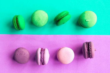 Geometrik yeşil ve mor arka planda yeşil ve pembe badem kurabiyeleri. Asgari konsept. 