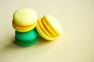 Sarı ve yeşil tatlı badem kurabiyeleri sarı arka planda, yakın plan 