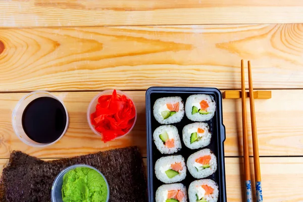一套寿司卷在盒子里 筷子放在木制桌子上 平面布局 顶视图 复制空间 — 图库照片
