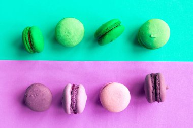 Geometrik yeşil ve mor arka planda yeşil ve pembe badem kurabiyeleri. Asgari konsept. 