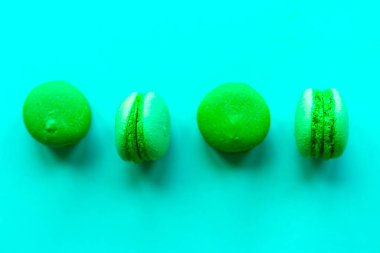 Renkli yeşil arka planda makarna, renkli Fransız makarnalı kurabiyelerin şablonu. Asgari konsept