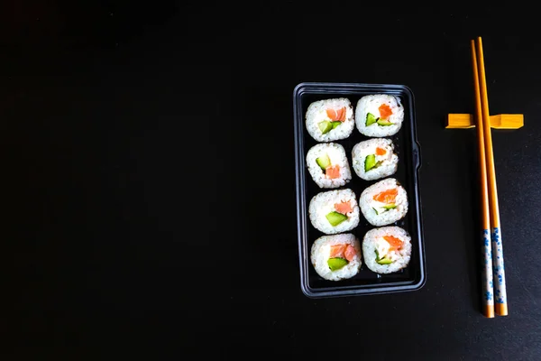 一套寿司卷在盒子里 筷子放在黑桌上 平面布局 顶视图 复制空间 — 图库照片