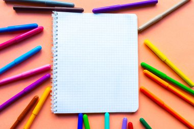Renkli kalemler ve pembe arka planda beyaz bir defter. Okul konseptine geri dönelim. Eğitim kavramı