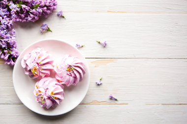 Tahta masanın üzerinde lezzetli krema ve leylak çiçekli bir dal var. Düz konum, üst görünüm, metin için boşluk kopyala