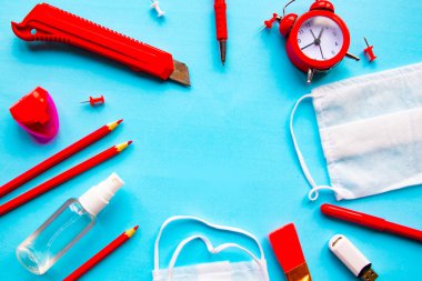 Mavi arka planda okul malzemeleri ve tıbbi maske var. Düz konum, üst görünüm, kopyalama alanı. Okul konseptine dönelim.