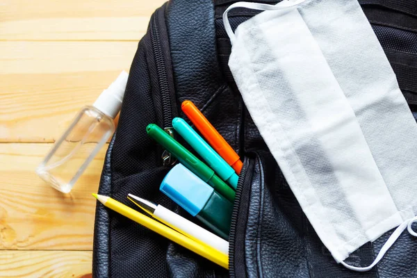 School bag, medical mask and pencils on wooden table. Back to school concept. School quarantine concept