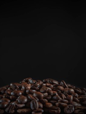 Kahverengi kahve çekirdekleri, koyu arkaplanda tohum. Koyu espresso, aroma, siyah kafein içeceği. Yakın çekim enerji mocha, cappuccino malzemesi.