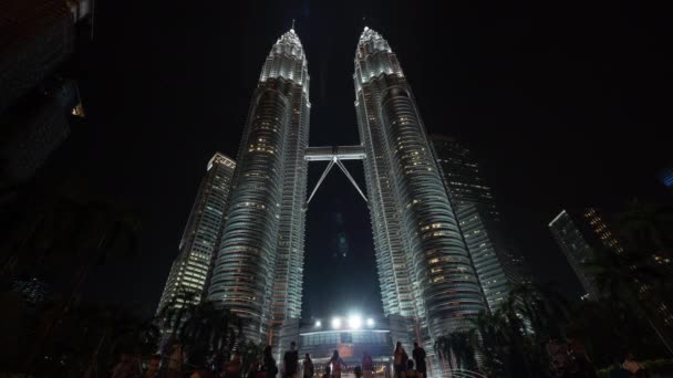 Time lapse view of Petronas Twin Towers at night from ground with people. Kuala Lumpur, Malaysia — ストック動画