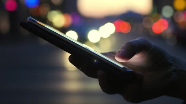 Vista de cerca del teléfono inteligente de iluminación contra la carretera de noche con los coches fondo de luz — Vídeo de stock