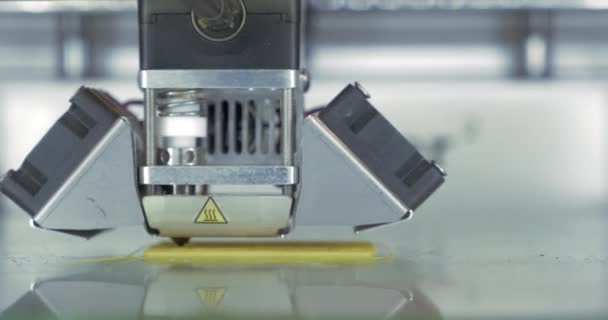 Vue rapprochée avant de l'imprimante 3D en cours. Il fabrique des pièces pour les équipements avec du plastique jaune — Video