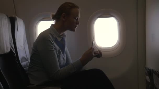 В представлении самолета женщина делает оплату с помощью банковской карты с помощью смартфона и ключа для сканирования банковской карты — стоковое видео