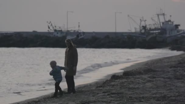 Mamma med son gå och leka på stranden av Egeiska havet på vintern. Néa Kallikrátia, Greece — Stockvideo