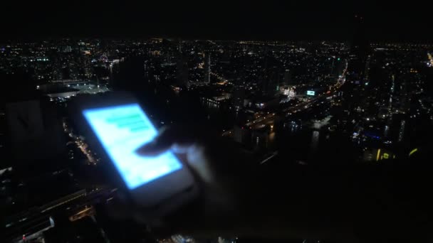 Chica escribiendo mensaje en el teléfono celular en el fondo de la ciudad de noche — Vídeo de stock