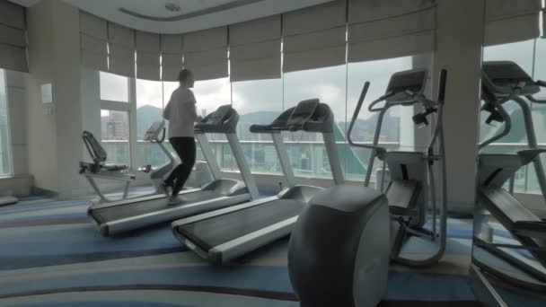 Mujer trabajando en la máquina de correr y mirando a la ciudad — Vídeo de stock