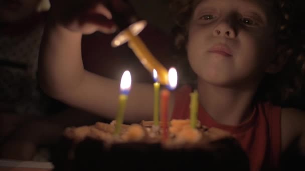 Vista en cámara lenta de la niña pequeña encendiendo las velas en el pastel de cumpleaños en la oscuridad — Vídeos de Stock