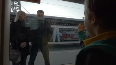 Saint-Petersburg, Rusya Federasyonu ağır çekimde platformda ayakta dedesi sallayarak tren penceresinden küçük çocuk