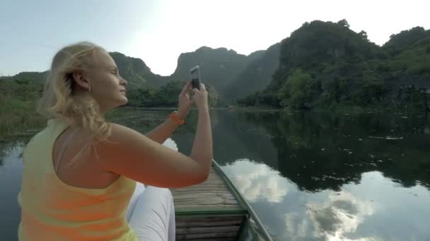 Female tourist taking photos with cell during boat in Trang An, Vietnam — Stock Video