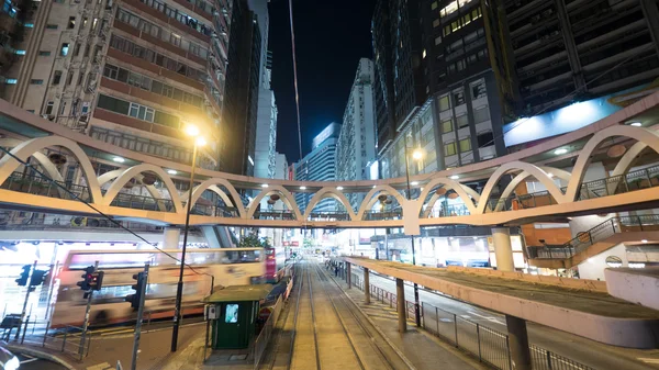 Illuminated street of Hong Kong with rails and pedestrian bridge — Stock Photo, Image
