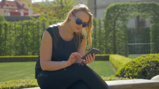 Mujer pasando el tiempo libre con la célula en el parque verde — Vídeos de Stock