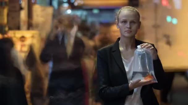 Zeitraffer: Frau mit Fisch in Plastiktüte inmitten der Menge — Stockvideo