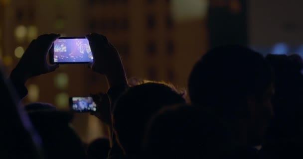 Espectador hombre grabación de vídeo con zoom de escenario y pantalla grande a través de smartphone en concierto de música al aire libre — Vídeos de Stock