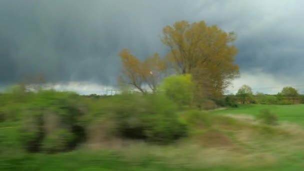 Uitzicht vanaf de trein naar natuur landschappen en zware wolken — Stockvideo