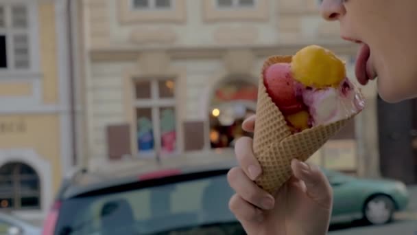 Slow motion close up van wandelen vrouw eet ijs ballen tegen ongericht stadsgezicht op de achtergrond, Prague, Tsjechië — Stockvideo