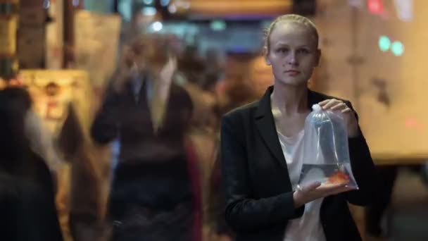 Тімелапс жінки з рибою в пластиковому пакеті серед натовпу — стокове відео