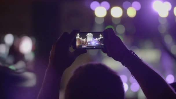 Spectator man hace una foto panorámica del escenario con proyectores a través de teléfono inteligente en el concierto de música al aire libre — Vídeo de stock