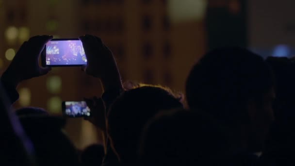 Spettatore uomo registrazione video con zoom del palco e grande schermo tramite smartphone al concerto di musica all'aperto — Video Stock