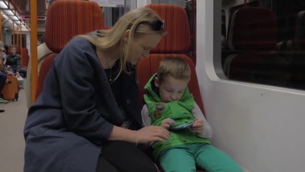 Criança e mãe com telefone celular em trem de metrô — Vídeo de Stock