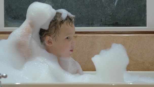 Enfant jouant avec la mousse dans le bain — Video