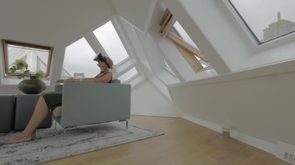 Ansicht einer jungen blonden Frau, die auf der Seite von Sesseln sitzt und Tabletten im Inneren eines Zimmers in einem Würfelhaus benutzt. Rotterdam, Niederlande — Stockvideo