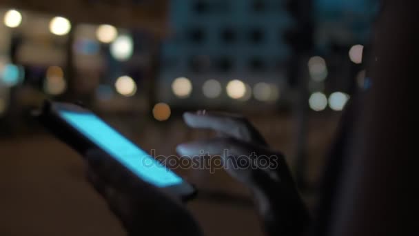 Vrouw te typen op mobiel wandelen in nacht stad — Stockvideo