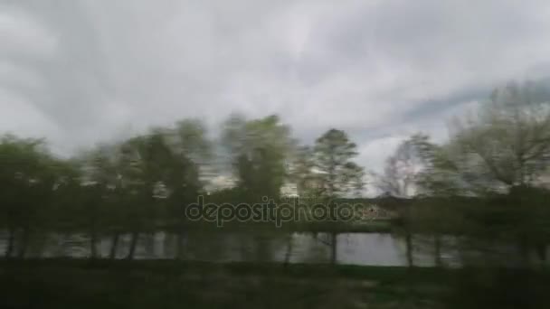 Vista desde la ventana del tren de equitación de paisaje de campo, árboles, bosques, casas contra el cielo nublado — Vídeos de Stock