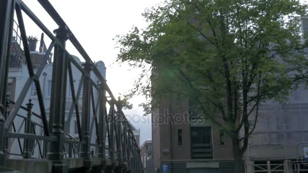 Vy över liten plastfigur av Iamsterdam bokstäver skulptur på bron mot suddig stadsbild, Amsterdam, Nederländerna — Stockvideo