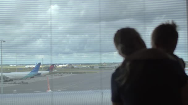 Niño y madre mirando aviones a través de la ventana — Vídeo de stock