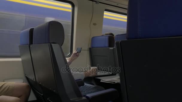 Vista de los hombres en el tren y trabajar con el ordenador portátil en la mesa y beber contra la ventana, Países Bajos — Vídeos de Stock