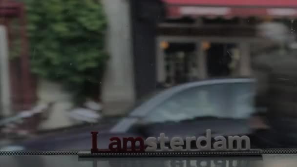 Vista da pequena figura plástica da escultura de letras de Iamsterdam na ponte contra a paisagem urbana turva, Amsterdã, Holanda — Vídeo de Stock