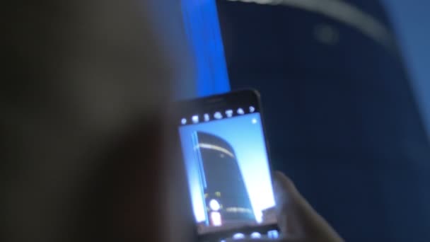 Vue rapprochée de la femme prenant une photo d'un immense gratte-ciel bleu par smartphone contre le ciel du soir, Rotterdam, Pays-Bas 